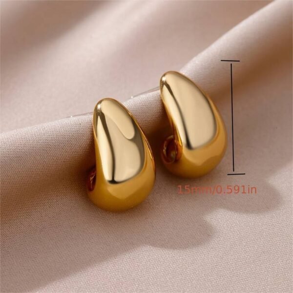 Close-up image of a pair of Water Drop Curved Shaped Stud Earrings in gold, placed on a light beige fabric background. A measurement scale shows the height of the earrings as 15mm or 0.591 inches.