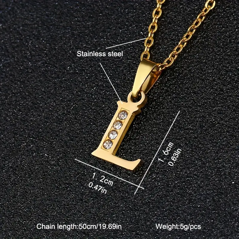 A close-up image of the Stainless Steel Letter Necklace showcases a gold-colored “L” pendant adorned with four small crystals, measuring 1.6 cm (0.63 in) in height and 1.2 cm (0.47 in) in width. The necklace features a 50 cm (19.69 in) chain and weighs 5g per piece.