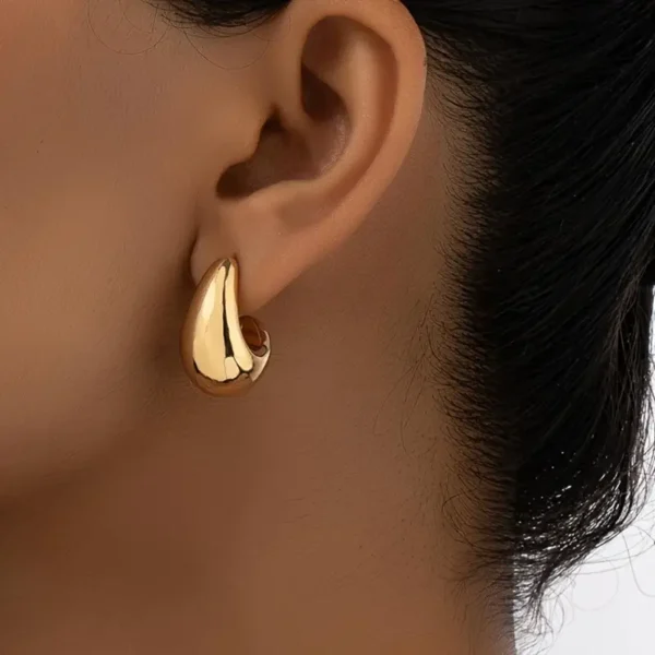 A close-up of a person's ear adorned with shiny Geometric Water Drop Earrings. The dark hair is pulled back, highlighting the earrings' polished finish and elegant design, perfect for daily wear.