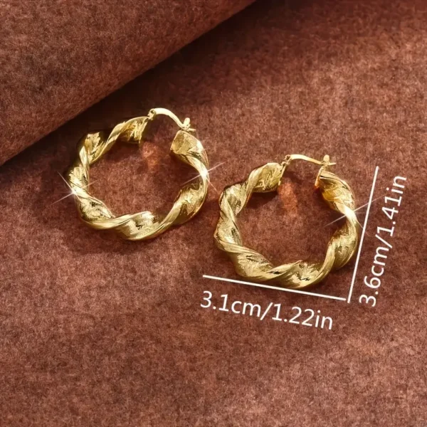 Twisted Rope Golden Hoops Earrings- Elegant Copper Gift displayed on a brown textured background. The shiny and reflective earrings have dimensions of 1.41 inches (3.6 cm) in height and 1.22 inches (3.1 cm) in width, making them a stunning addition to any jewelry collection.