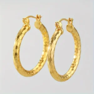 The 14K Gold Plated Delicate Hoop Earrings - Vintage Bohemian Style showcase a textured, checkered pattern. These medium-sized hoops are designed with a clasp mechanism for secure wear, and their plain, light-colored background highlights their shine and intricate details.