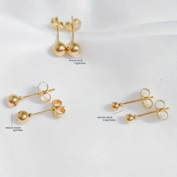 Three pairs of Golden Ball Stud Earrings: Punk Style, Everyday Stainless Steel are displayed on a white surface. These minimalist gold stud earrings come in various sizes and weights: 5mm/0.2in/1.5g/0.05oz, 4mm/0.16in/1g/0.04oz, and 3mm/0.12in/0.5g/0.02oz.