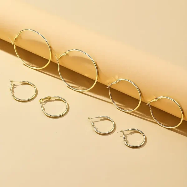 The 4 Pair Hoop Earrings Set: Minimalist, Stainless Steel, Everyday Chic is showcased on a beige background. These gold hoop earrings come in four pairs of varying sizes, arranged neatly from largest at the top to smallest at the bottom.