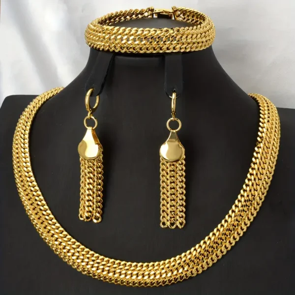 The Hip Hop Miami Cuban Necklace and Bangle Earrings Set is showcased on a sleek black stand. This unisex fashion ensemble comprises a substantial Miami Cuban necklace, a coordinating bracelet, and dangling earrings, each adorned with intricately interlinked gold chains. The set exudes elegance against the simple white fabric backdrop.