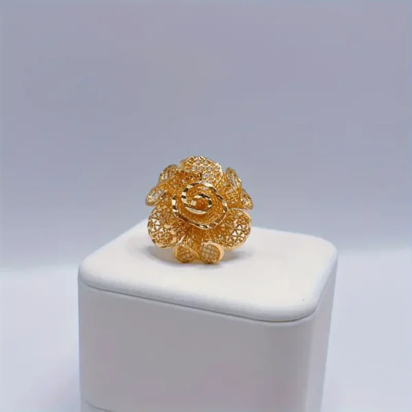 The Exquisite Flower Open Ring - Golden Luxury Copper for Romantic Gifts is showcased on a white cushioned platform against a plain background. The intricate rose-shaped design features delicate petal patterns and textured surfaces, highlighting the detailed craftsmanship and creating an elegant, ornate appearance.