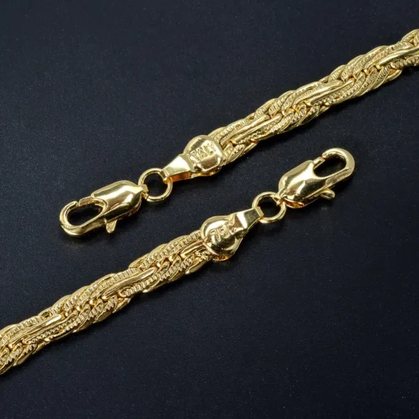 Close-up of two intertwined Golden Chains, 0.2 inches wide with intricate designs and lobster claw clasps, placed on a dark background. The highly polished chains and clasps give them a shiny appearance, making them perfect as a dainty gift in the form of the Golden Chain 0.2inch Wide Long Geometric Necklace.