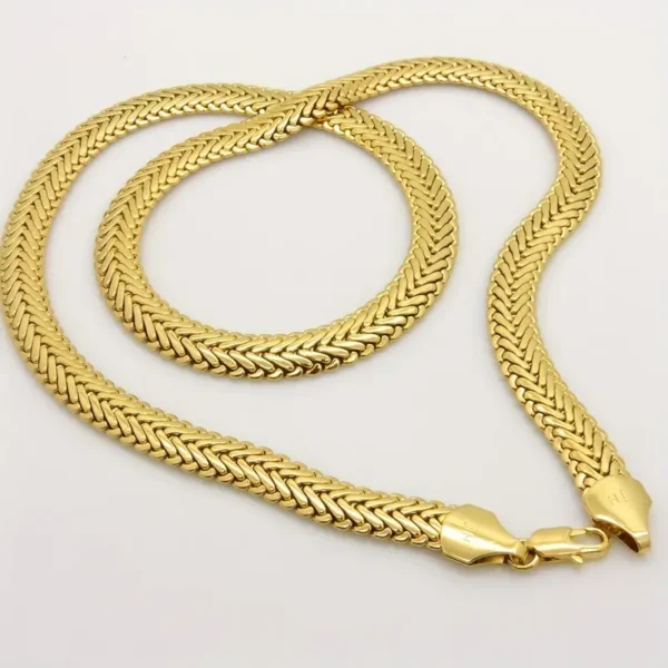 A close-up of Hip Hop Royalty: Gold Plated Herringbone Set with a lobster clasp. The hip hop jewelry piece features a thick, intricately woven pattern and is laid out flat in a circular shape on a plain white background.