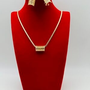 The 18k Gold Plated Bridal Jewelry Set - Geometric & Tribal Elegance displayed on a red velvet stand features gold and rhinestone-encrusted rectangular pendants: the necklace has a single pendant on a thin chain, and the earrings are matching with hanging rectangular pendants.