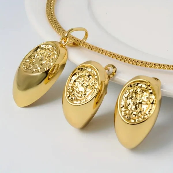 A close-up image of the Luxury Geometric Copper Jewelry Set - Necklace & Earrings, Unplated Elegance, featuring a sophisticated pendant necklace with a thick chain and two matching earrings. Each piece showcases an oval-shaped pendant adorned with intricate, textured detailing at its center. The jewelry is elegantly displayed on a white ceramic surface.