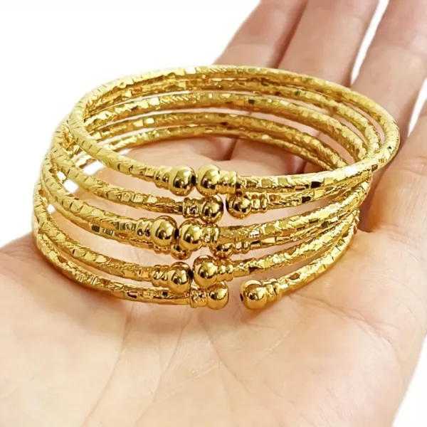 a hand holding a stack of gold bracelets