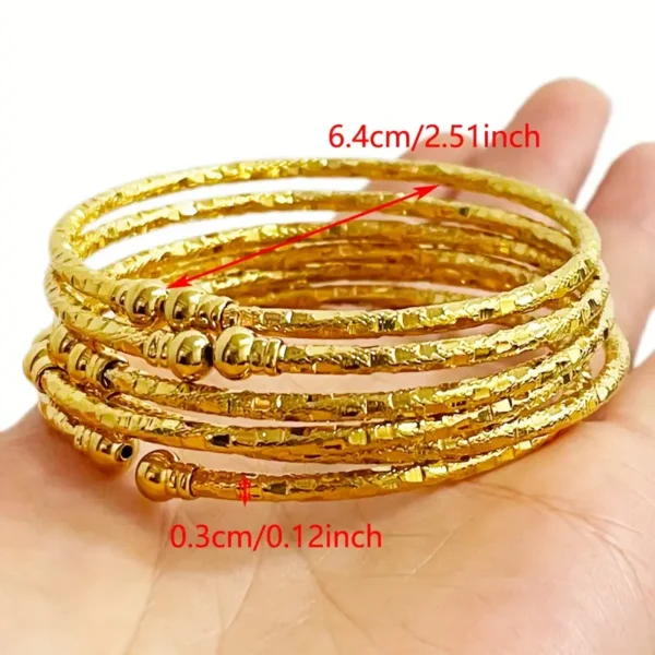 a hand holding a stack of gold bracelets