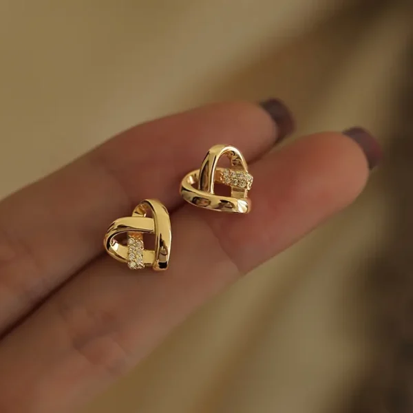 a person holding a pair of gold earrings