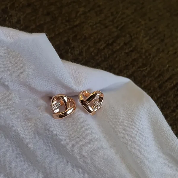 a pair of gold earrings on a white fabric